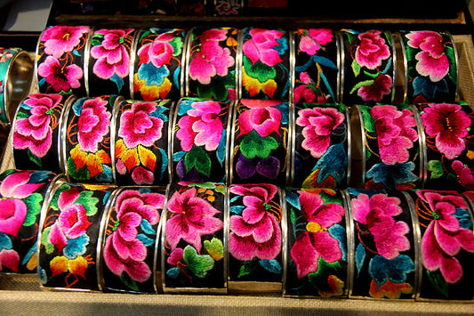 Miao hand-embroidered festival flower bangles in assorted tray display