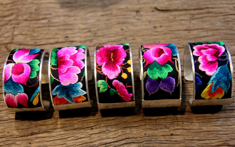 Five assorted Miao hand-embroidered open cuff bangles on wood