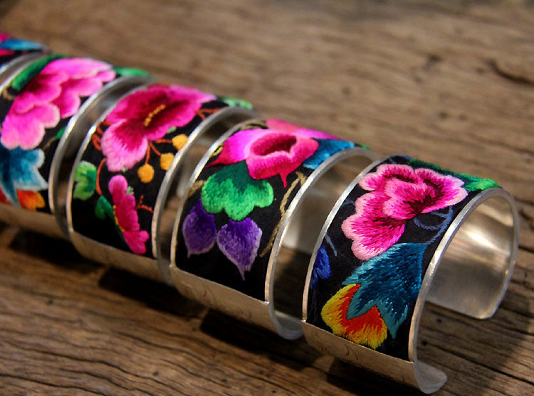 Angled row of electroplated silver bangles with hand-embroidered floral textile